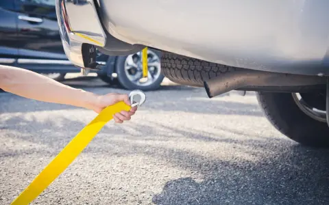 Ręka trzymająca żółtą linę do holowania, przygotowująca do holowania na autostradzie.