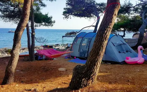 Idealne wakacje: chorwacja pod namiotem, z hamakiem, dmuchanym flamingiem i widokiem na morze.