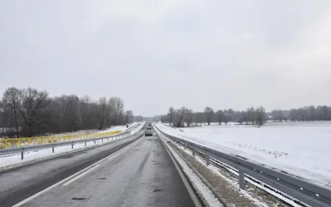 Zimowa trasa, śnieg przy drodze, drzewa bez liści. Nowy tomyśl trasa wita podróżnych.