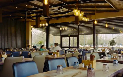 Przytulna restauracja z drewnianymi elementami i designerskimi lampami. Idealne miejsce na dobre jedzenie na trasie Kraków-Zakopane.