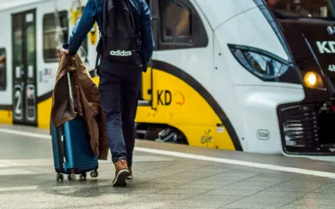 Podróż z Warszawy do Kołobrzegu pociągiem. Mężczyzna z walizką i plecakiem wchodzi do pociągu.