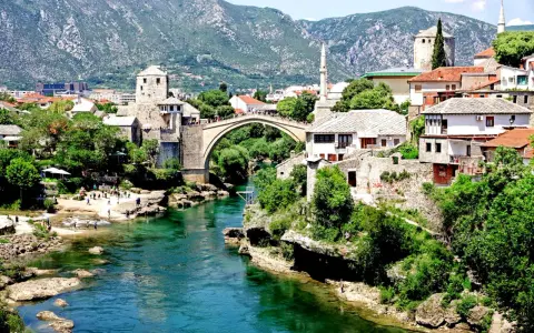 Mostar, Bośnia i Hercegowina: zielona karta dla turystów. Stary Most i rzeka Neretwa w letnim słońcu.