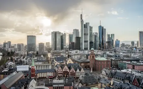 Widok na nowoczesne i zabytkowe frankfurt nad menem dzielnice, z drapaczami chmur i kościołami pod zachodzącym słońcem.