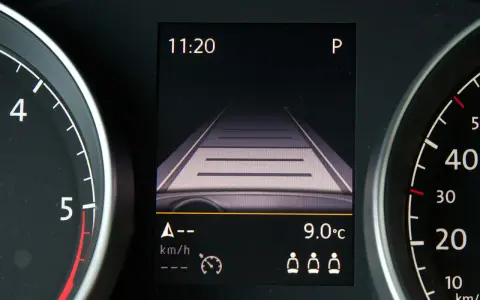 Wyświetlacz w samochodzie pokazuje widok drogi, zegar 11:20 i temperaturę 9°C. To pomocne informacje, gdy zastanawiasz się, tempomat co to jest i jak działa.