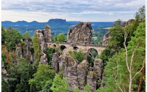 Kamienny most Basteibrücke w Szwajcarskiej Saksonii, łączący skalne baszty pośród zielonych lasów i gór.