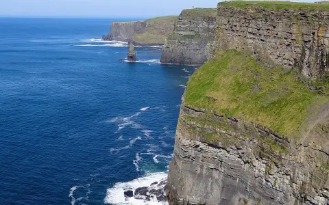 Majestatyczne klify Irlandii wznoszą się nad błękitnym oceanem. Zielone zbocza kontrastują z szarymi skałami, tworząc zapierający dech w piersiach krajobraz.