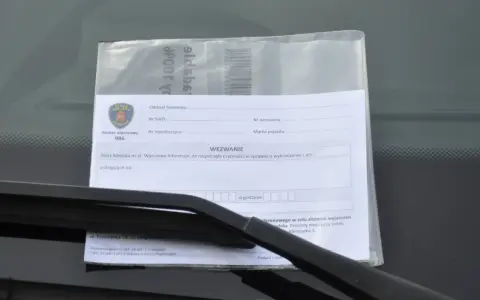 Wezwanie od Straży Miejskiej za złe parkowanie. Dokument zawiera pieczęć Straży Miejskiej Warszawa, numer alarmowy 986 i pole do wpisania przyczyny wezwania.