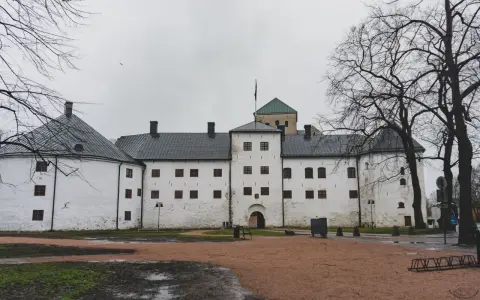 Biały zamek z wieżą i zielonym dachem, symbol najstarszego miasta w Finlandii.