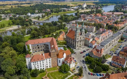 Zamek Piastów Śląskich w otoczeniu miasta i rzeki. Zabytkowa budowla z czerwonymi dachami, obok katedra z zielonymi wieżami.