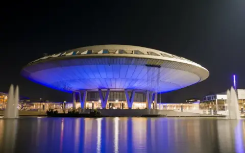 Futurystyczny budynek w Eindhoven, oświetlony niebieskim światłem, z fontannami w stawie. Jedna z głównych eindhoven atrakcji.
