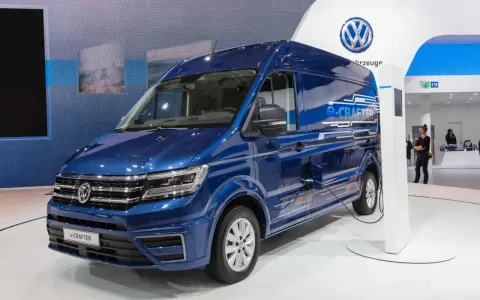 Niebieski kamper elektryczny e-Crafter podłączony do ładowarki na stoisku Volkswagena.