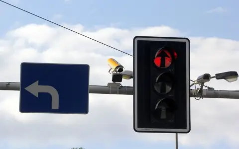 Fotoradar na światłach, czerwone światło dla kierunku na wprost. Obok znak nakazu skrętu w lewo.