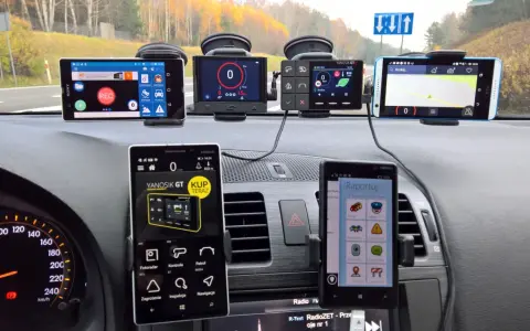 Na desce rozdzielczej samochodu zamontowano kilka urządzeń nawigacyjnych i telefonów, które pomagają w podróży. Widać prędkościomierz i mapę. Ta piła trasa była dobrze przygotowana.