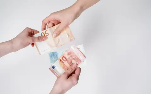 Dwie ręce przekazują sobie banknoty euro. W Austrii obowiązuje euro, co widać na przykładzie tych banknotów.