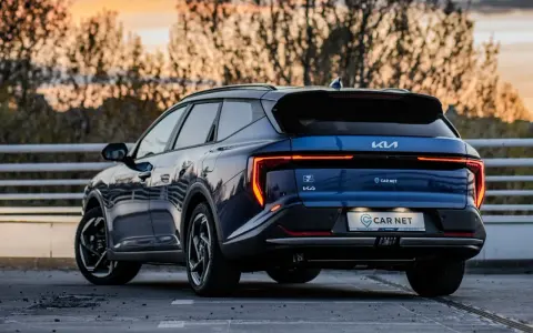 Niebieskie Kia EV6 gotowe na podróż z Poznania do Jeleniej Góry. Zachód słońca nad drzewami.