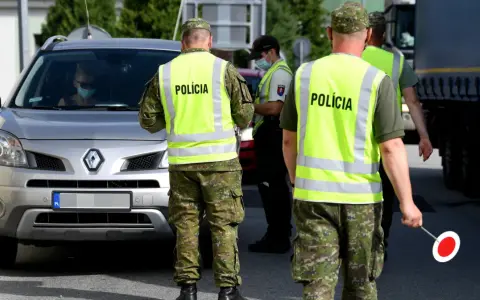 Policjanci w kamizelkach odblaskowych kierują ruchem podczas przejazdu przez Słowację. Kierowca w masce zatrzymuje się do kontroli.