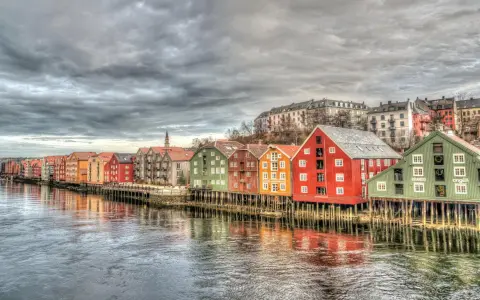 Kolorowe domy na palach wzdłuż rzeki, przypominające malownicze trondheim fiordy.