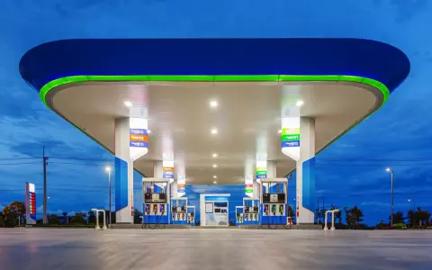 Stacja paliw z podświetlanym zadaszeniem i dystrybutorami. Widoczne ceny paliw, np. Diesel B10, Gasohol 95, E20.