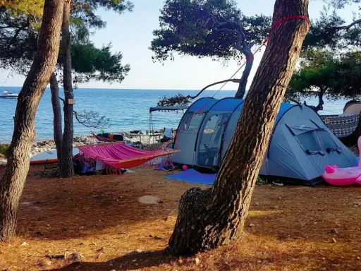 Idealne wakacje: chorwacja pod namiotem, z hamakiem, dmuchanym flamingiem i widokiem na morze.