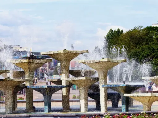 Wielopoziomowa fontanna w Gdyni, z wodą tryskającą na tle miasta. Trasa Gdynia tętni życiem obok tej wodnej atrakcji.