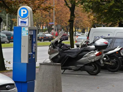 Parkomat z symbolem "P" i skuterem obok. Upewnij się, że masz ważny bilet, by uniknąć mandatu za parkowanie.