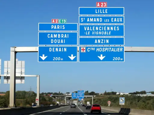Znaki drogowe na autostradzie we Francji wskazują drogę do Lille, Paryża, Cambrai, Douai i Denain.