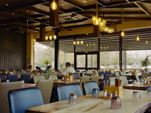 Przytulna restauracja z drewnianymi elementami i designerskimi lampami. Idealne miejsce na dobre jedzenie na trasie Kraków-Zakopane.