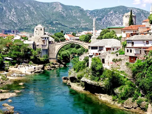 Mostar, Bośnia i Hercegowina: zielona karta dla turystów. Stary Most i rzeka Neretwa w letnim słońcu.