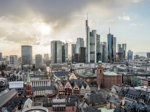 Widok na nowoczesne i zabytkowe frankfurt nad menem dzielnice, z drapaczami chmur i kościołami pod zachodzącym słońcem.