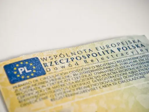 Dowód rejestracyjny pojazdu, niezbędny do ubezpieczenia auta, z flagą PL i tekstem w wielu językach.