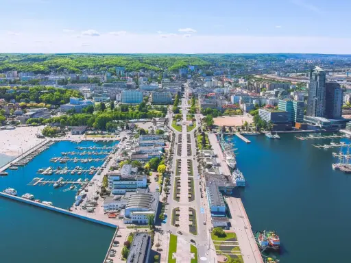 Widok na Gdynię z lotu ptaka. Widać port jachtowy, plażę i zabudowę miejską. Odległość do Wejherowa jest spora, ale widok zapiera dech.