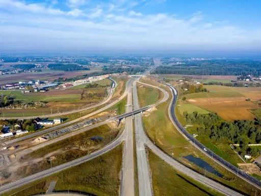 Rozbudowa trasy gdańsk, widok z lotu ptaka na węzeł drogowy w otoczeniu pól i lasów.