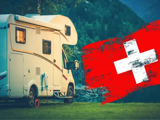 Kamper na tle gór i flagi Szwajcarii. Idealne miejsce na podróż kamperem po Szwajcarii.