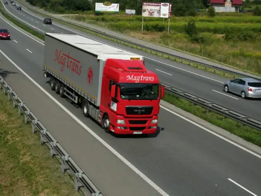 Czerwony tir Magtrans jedzie autostradą. Kierowca może otrzymać mandat za wyprzedzanie tirem w niewłaściwym miejscu.