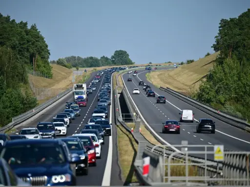 Korek samochodów na autostradzie A1, zieleń po bokach, błękitne niebo.