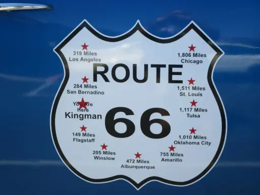 Tablica z napisem "ROUTE 66" i odległościami do miast, w tym "You Are Here Kingman".