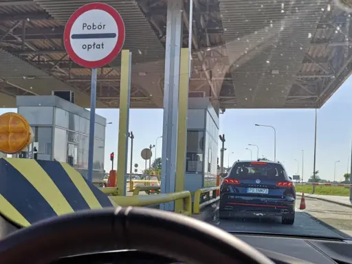 Kolejka samochodów do punktów poboru opłat. Znak informuje o poborze opłat.