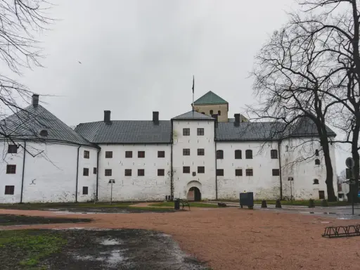 Biały zamek z wieżą i zielonym dachem, symbol najstarszego miasta w Finlandii.