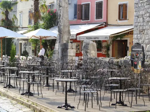 Letni dzień na półwyspie Istria. Pusta kawiarnia z czarnymi, metalowymi stolikami i krzesłami czeka na gości.