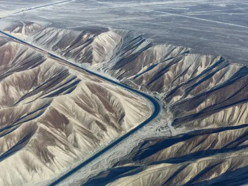 Droga przecina pustynny krajobraz z licznymi wzgórzami, przypominając najdłuższą autostradę na świecie.