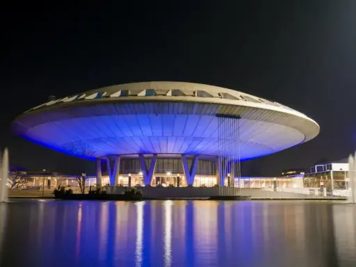 Futurystyczny budynek w Eindhoven, oświetlony niebieskim światłem, z fontannami w stawie. Jedna z głównych eindhoven atrakcji.