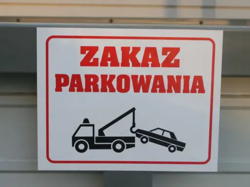 Zasady parkowania na parkingu: zakaz parkowania, holowanie pojazdów. Znak ostrzega przed odholowaniem źle zaparkowanego auta.