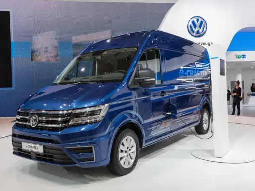 Niebieski kamper elektryczny e-Crafter podłączony do ładowarki na stoisku Volkswagena.