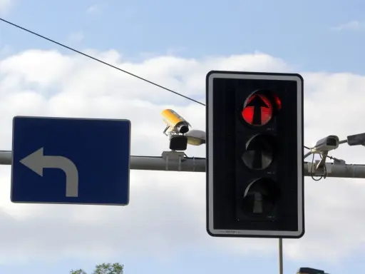 Fotoradar na światłach, czerwone światło dla kierunku na wprost. Obok znak nakazu skrętu w lewo.