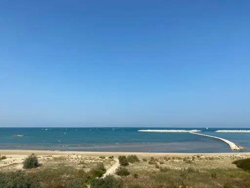 Piękny dzień nad morzem w Pescara i okolice. Wiele żaglówek na turkusowej wodzie, piaszczysta plaża i falochrony.