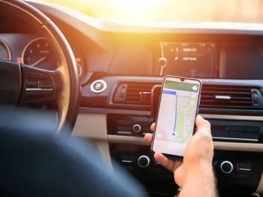 Kierowca używa nawigacji na telefonie. Zastanawia się, ile punktów karnych za telefon grozi za takie zachowanie.