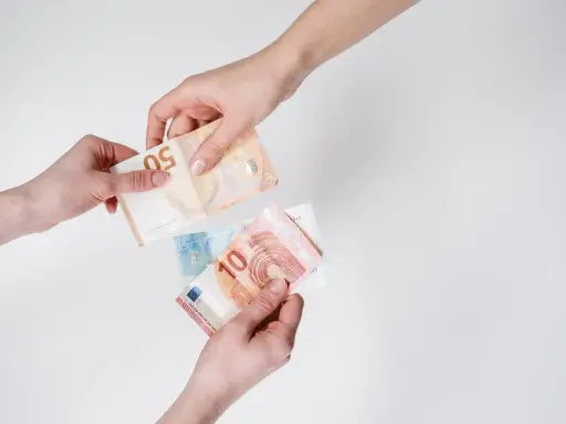 Dwie ręce przekazują sobie banknoty euro. W Austrii obowiązuje euro, co widać na przykładzie tych banknotów.
