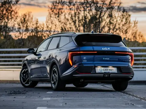 Niebieskie Kia EV6 gotowe na podróż z Poznania do Jeleniej Góry. Zachód słońca nad drzewami.