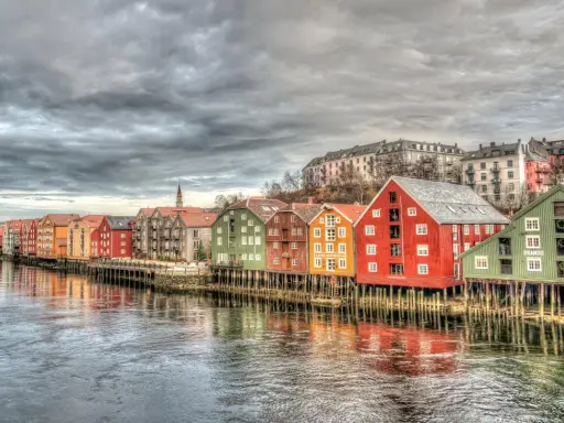 Kolorowe domy na palach wzdłuż rzeki, przypominające malownicze trondheim fiordy.