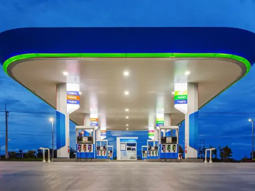 Stacja paliw z podświetlanym zadaszeniem i dystrybutorami. Widoczne ceny paliw, np. Diesel B10, Gasohol 95, E20.